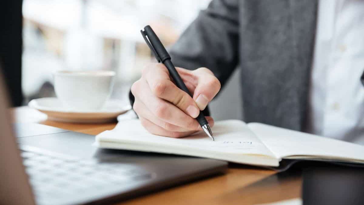 muž píše zhrnutie do svojho zápisníka
